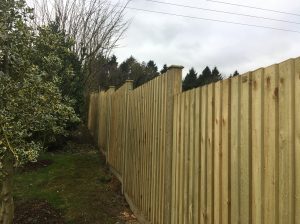 Featherboard fence panels on slotted fence posts